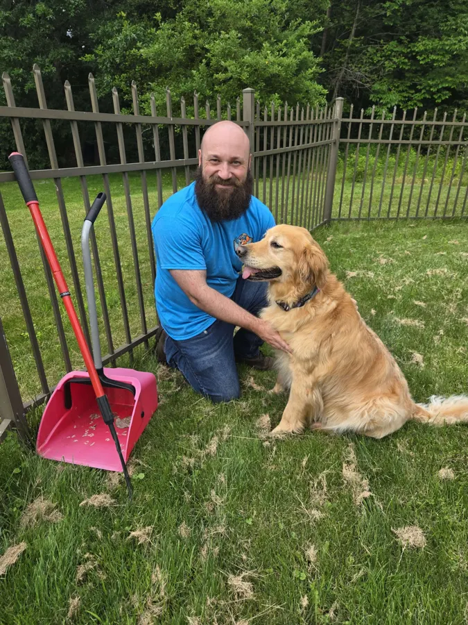 Landmine Patrol team member with a golden retriever and a pooper scooper