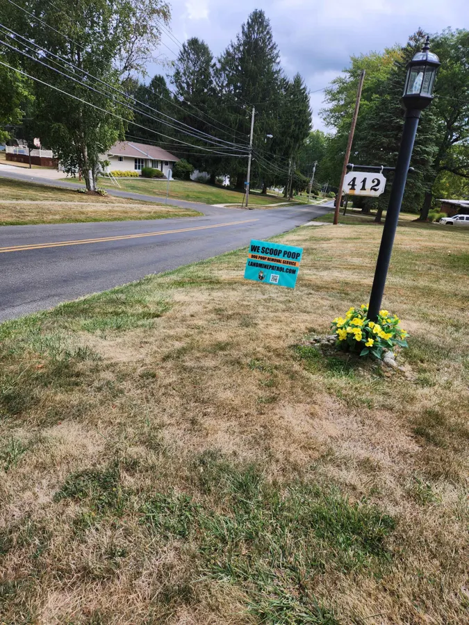 Landmine Patrol 'We Scoop Poop' yard sign in a customer's front yard